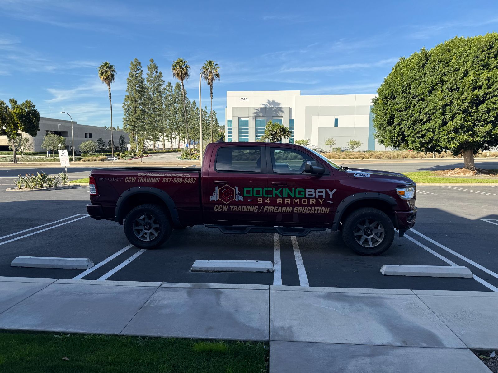 Driver side of a maroon Ram pickup with Docking Bay 94 Armory graphics: cast vinyl logo, 'CCW Training / Firearm Education' lettering, website and phone number across the cab and bed, installed by Hi Sign, Brea, CA