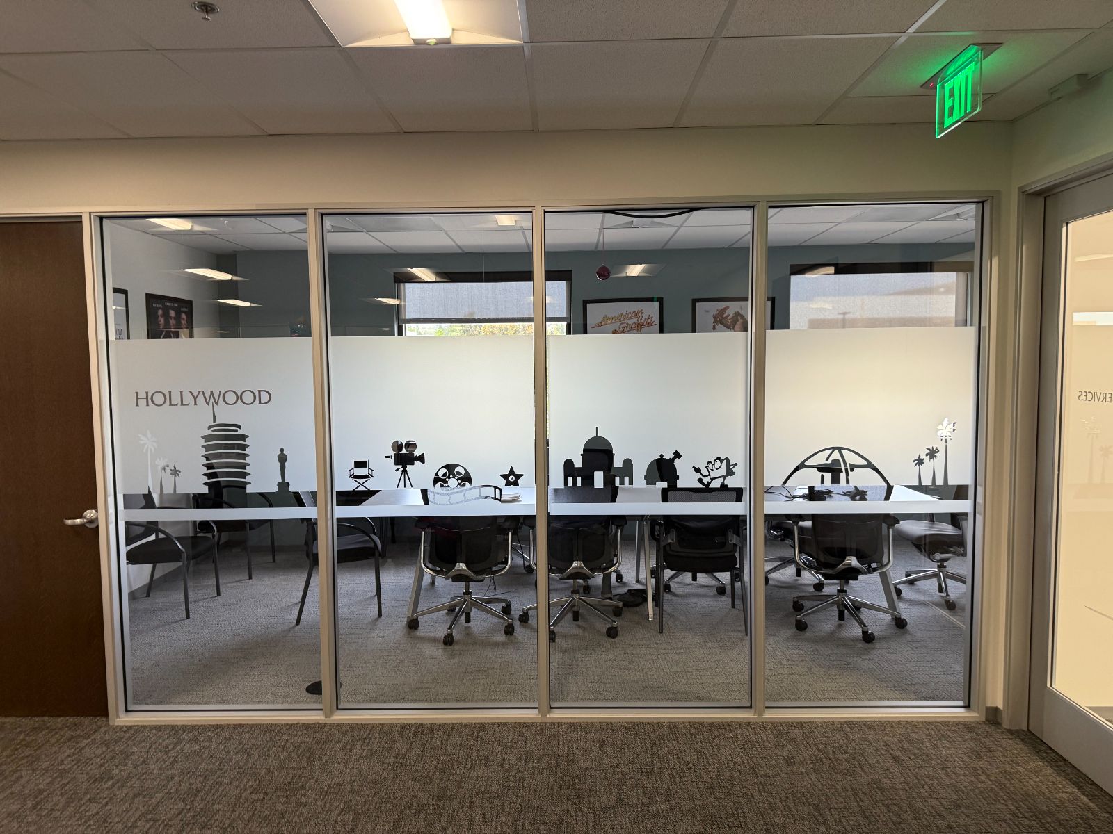 Glass-walled conference room with a frosted privacy band across the lower glass, decorated with a black Hollywood-themed skyline of film icons and the word HOLLYWOOD, installed by Hi Sign, Brea, CA