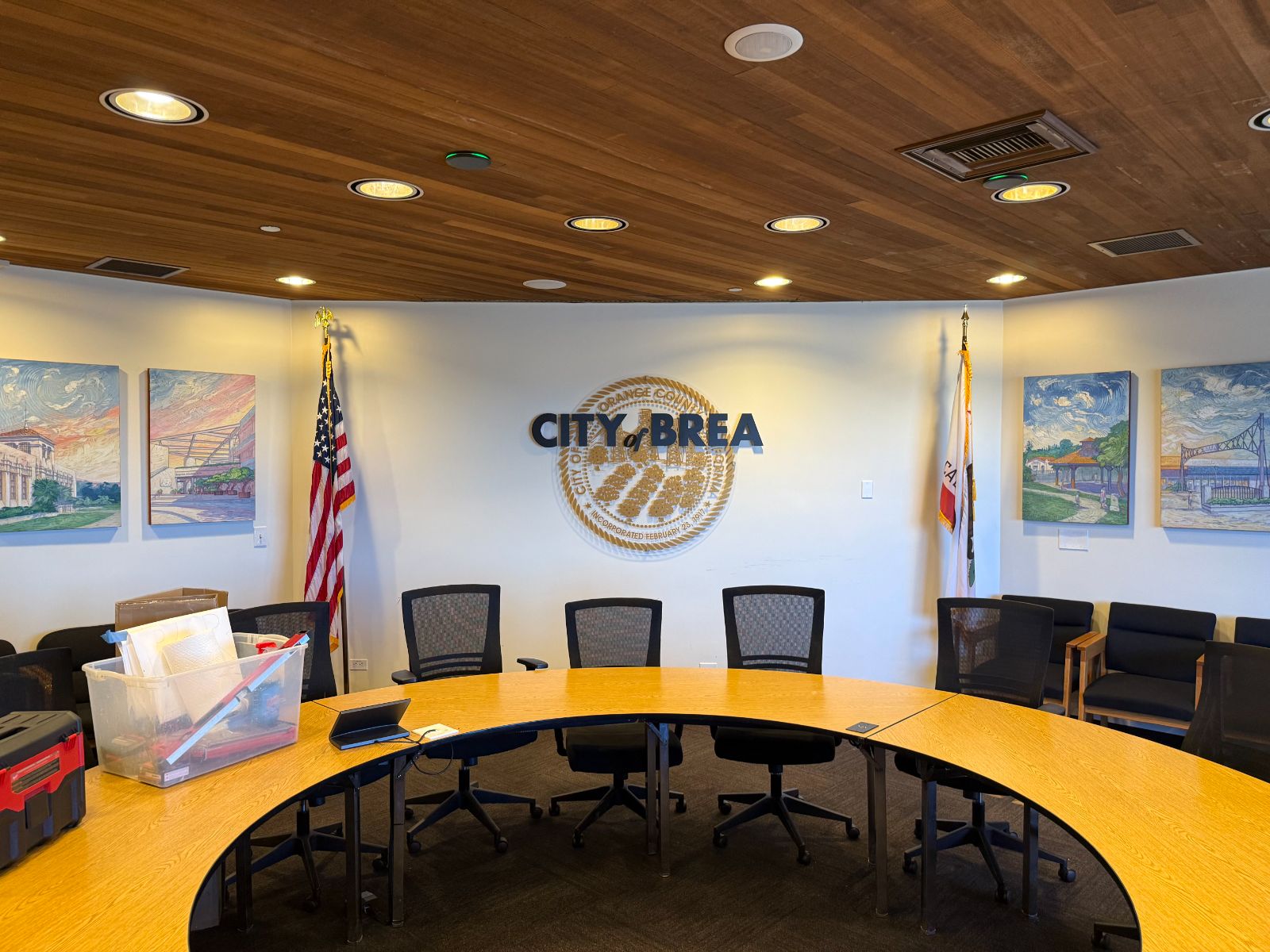 City of Brea council chamber wall: dark blue dimensional 'City of Brea' letters over a printed gold city seal, flanked by flags and framed paintings, beneath a wood-slat ceiling, installed by Hi Sign, Brea, CA