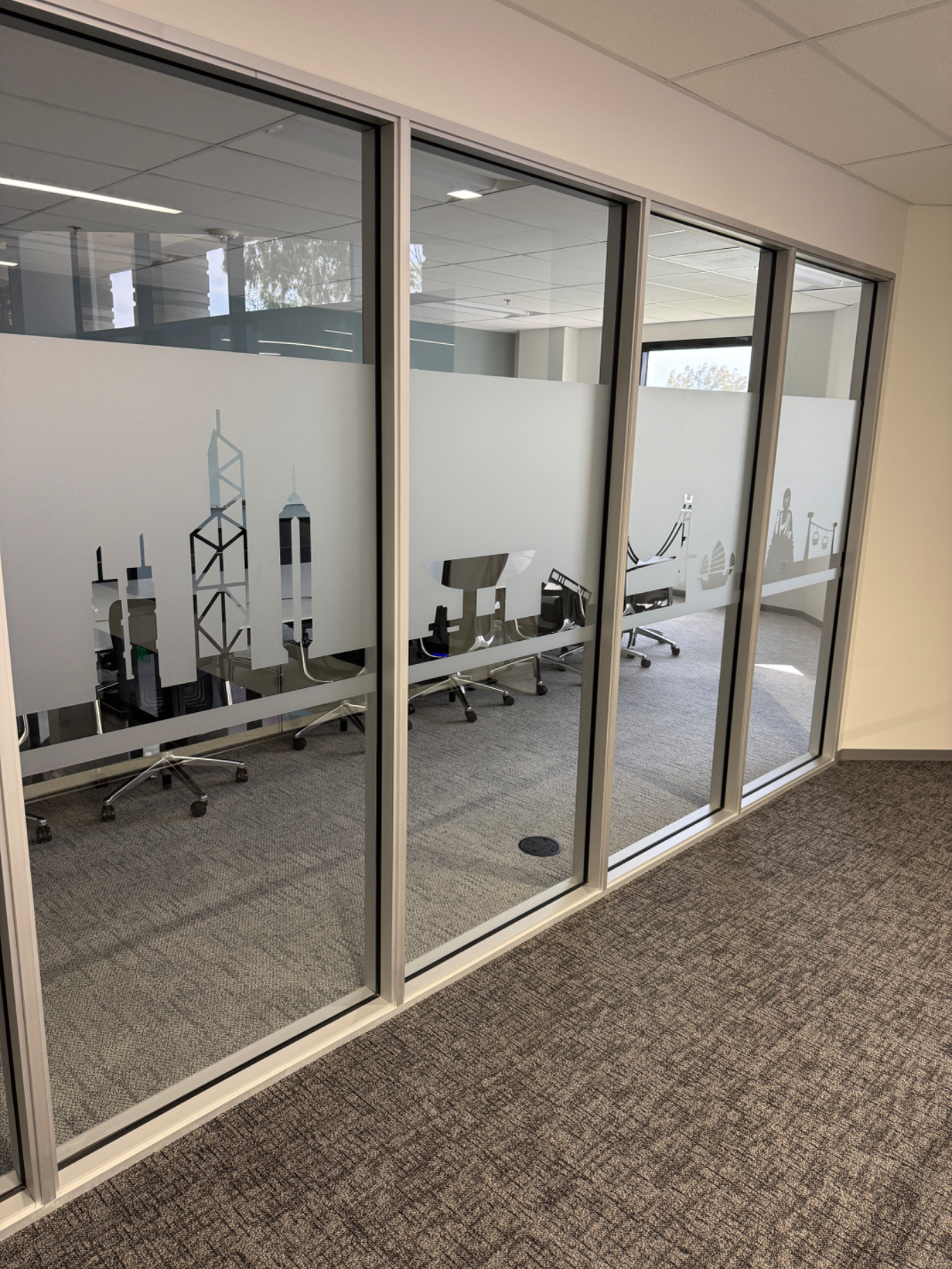 Long run of glass office wall with a continuous frosted privacy band carrying cut-vinyl city skyline graphics, installed by Hi Sign, Brea, CA