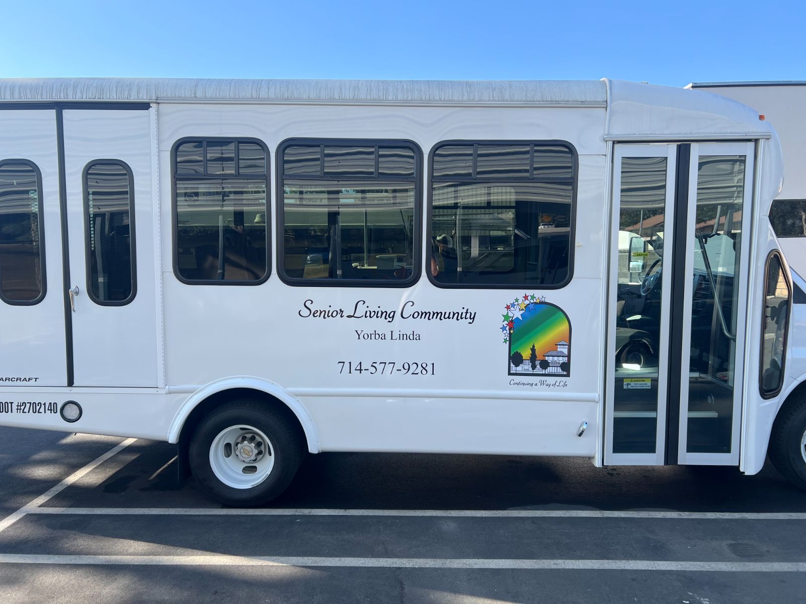 Passenger-side vehicle graphics on the same Starcraft shuttle bus: vinyl die-cut logo and cut lettering with business name, city, and phone number applied to the exterior body panel, installed by Hi Sign, Brea, CA