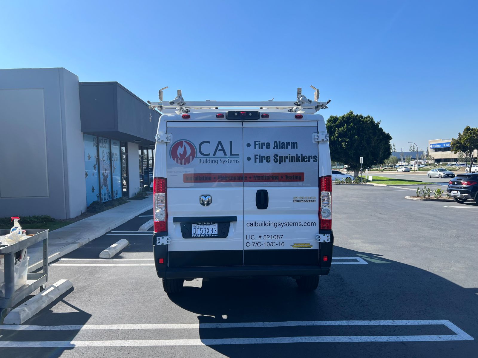 Rear doors of the same white CAL Building Systems van: vinyl logo, service list, website, and contractor license numbers applied across the back, installed by Hi Sign, Brea, CA