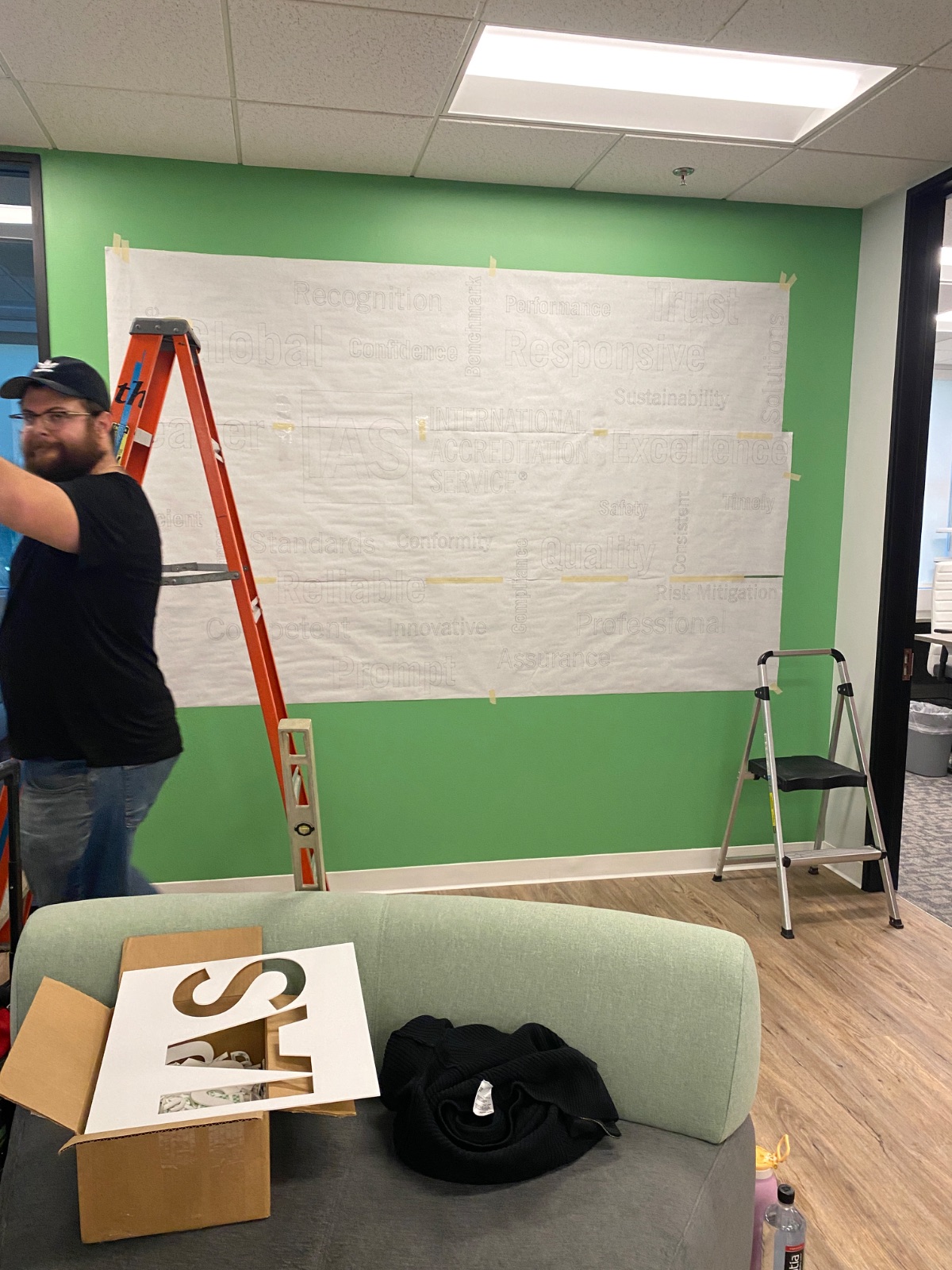 Install in progress: application tape masking the upper wall while the vinyl is positioned from a ladder, installed by Hi Sign, Brea, CA
