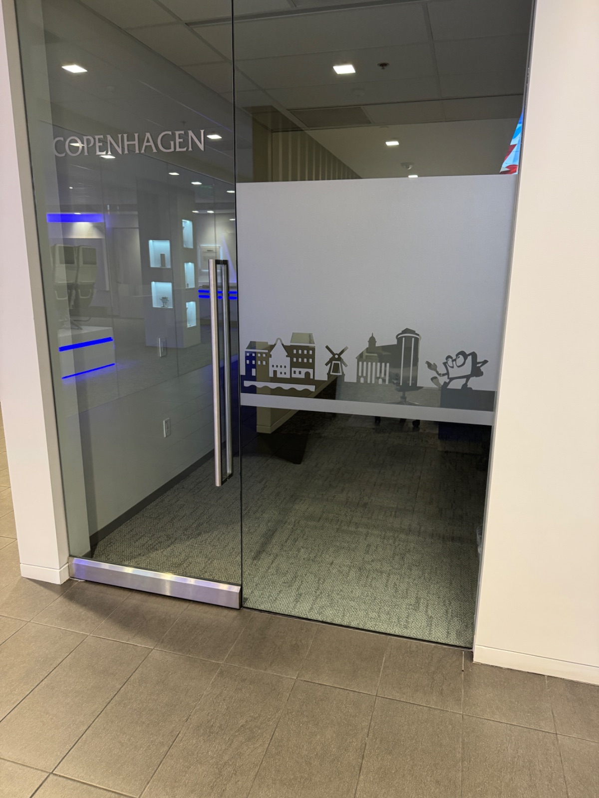 Angled view of the frosted glass room front, showing the Copenhagen skyline graphic and room name across two glass panels, installed by Hi Sign, Brea, CA