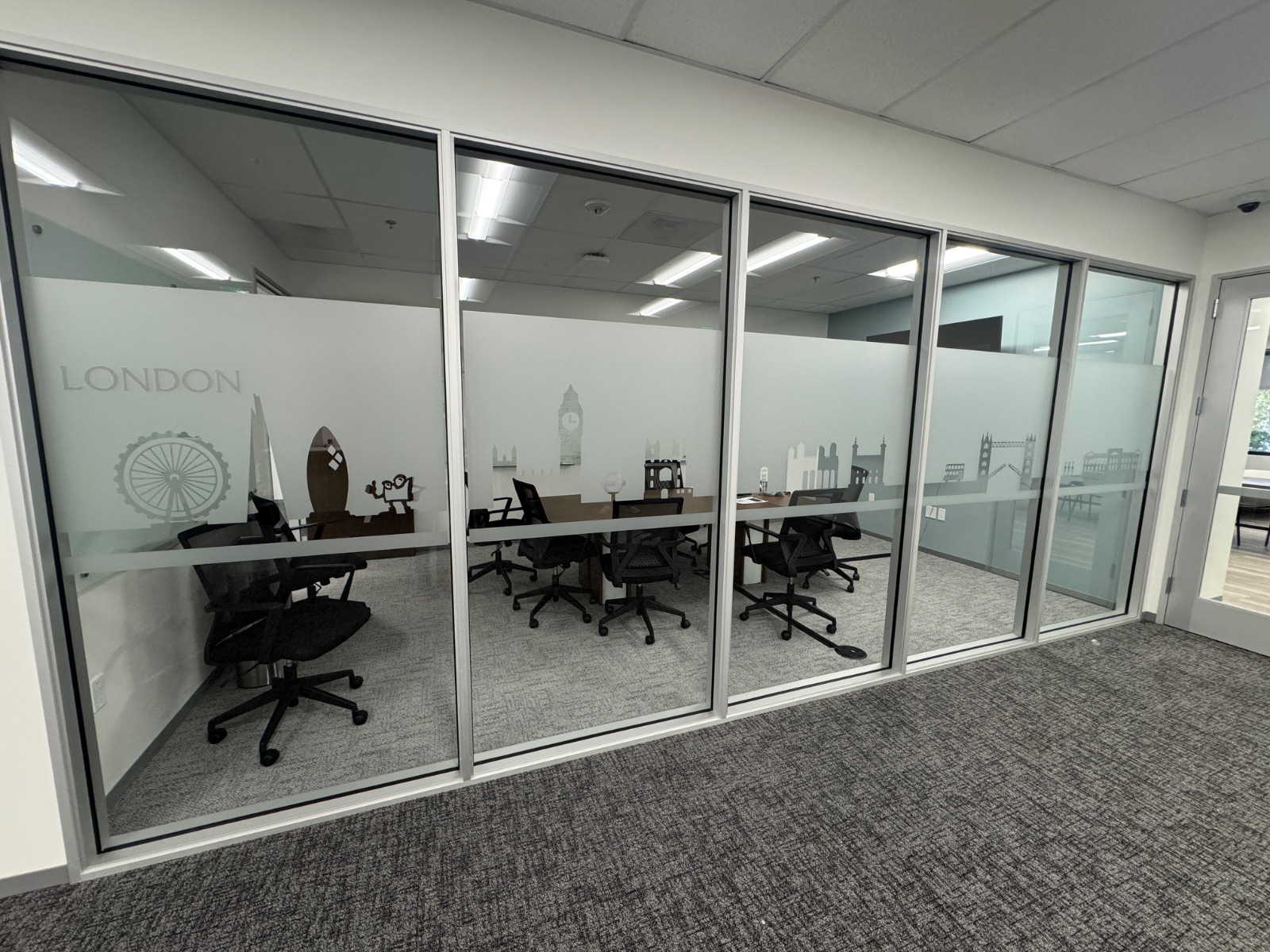 Long run of glass office fronts with continuous frosted privacy film and cut-vinyl London landmark graphics, installed by Hi Sign, Brea, CA