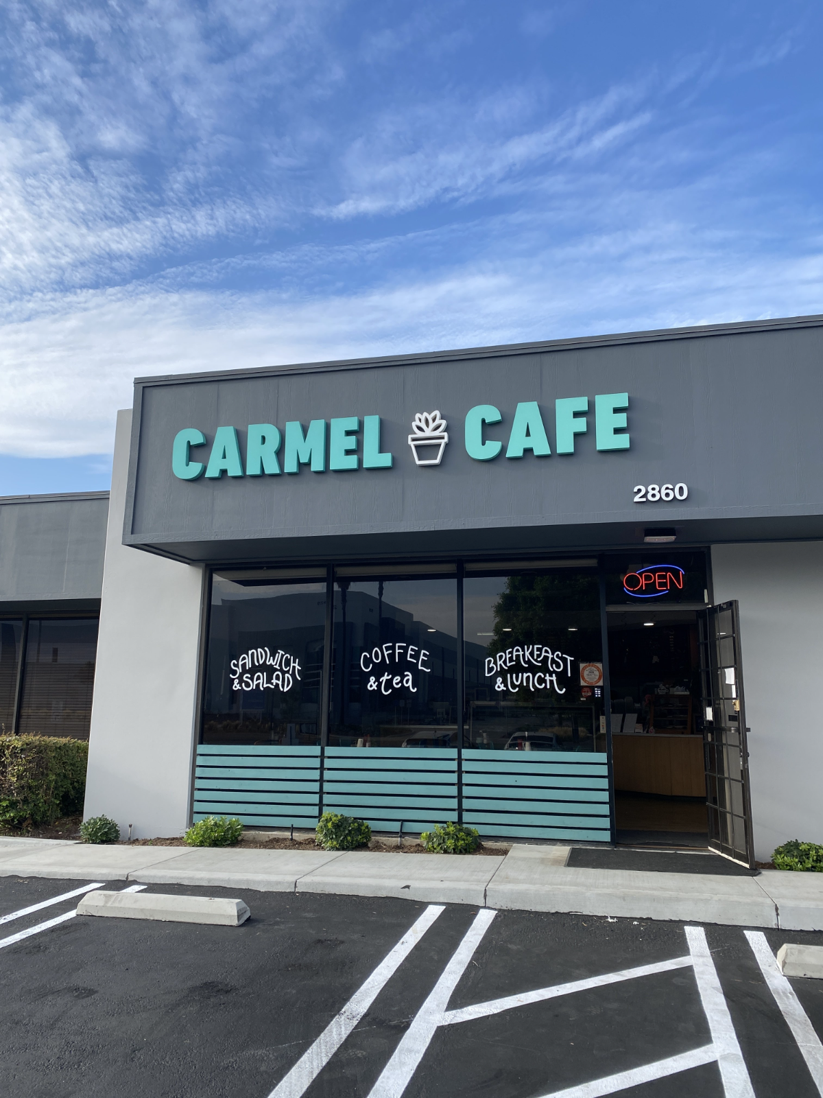 Storefront fascia for Carmel Cafe: teal dimensional letters and a potted-plant logo mounted on a gray fascia band, with hand-lettered window vinyl reading Sandwich & Salad, Coffee & Tea, Breakfast & Lunch, installed by Hi Sign, Brea, CA