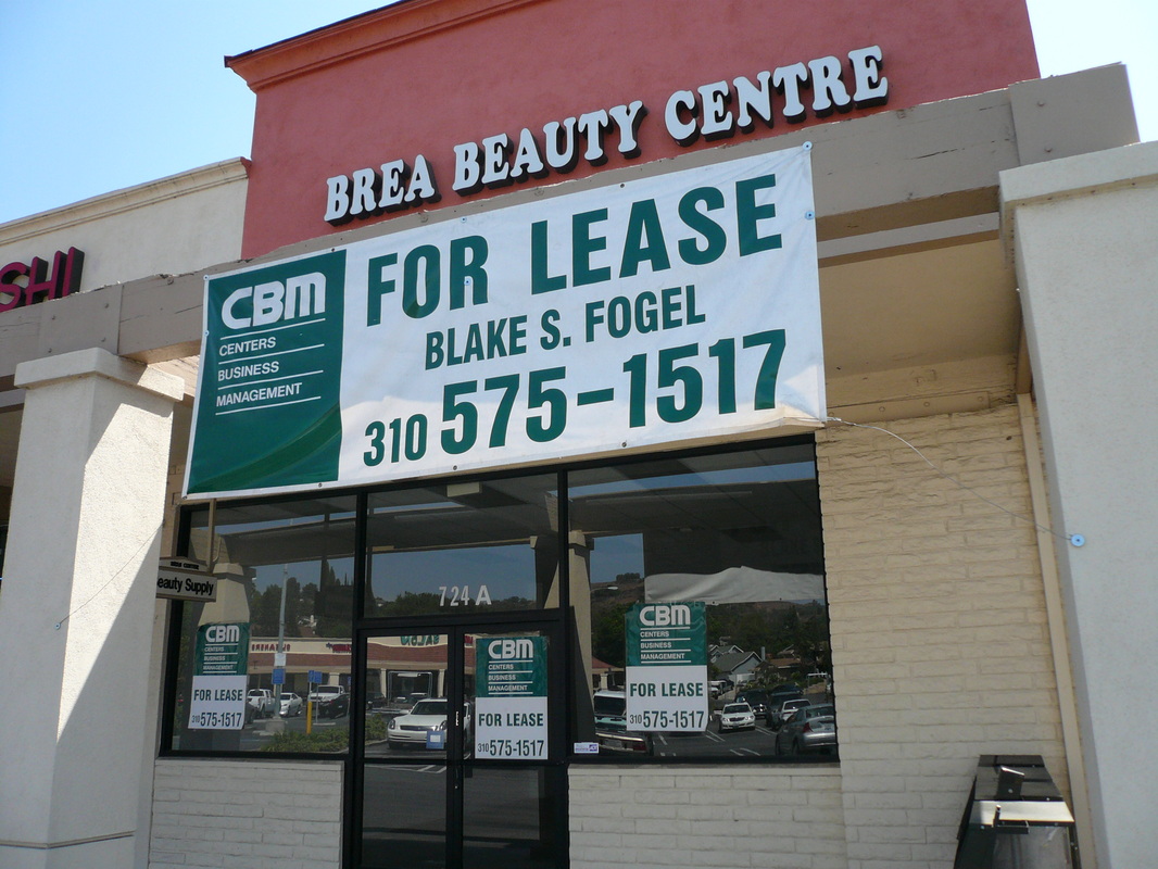 Large white vinyl 'For Lease' banner with green type and a CBM logo, grommet-mounted across a retail storefront fascia, with matching window signs below, installed by Hi Sign, Brea, CA